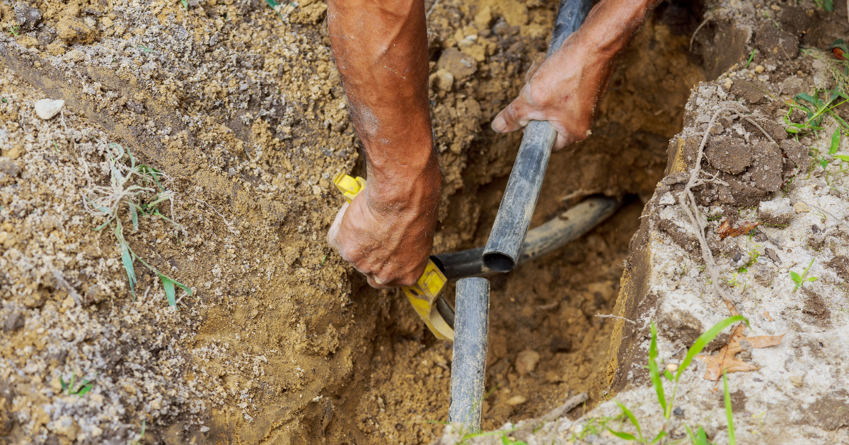 Technician replacing a sprinkler head at a Fairburn property entrance